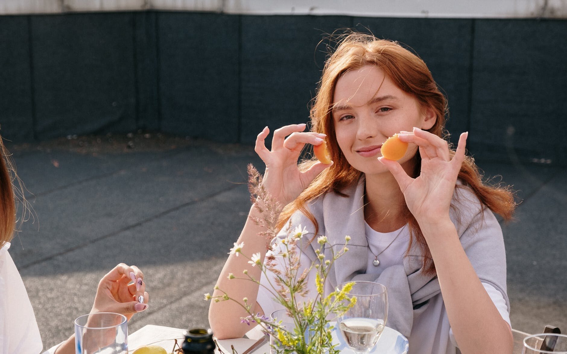woman in white dress shirt holding orange fruit
