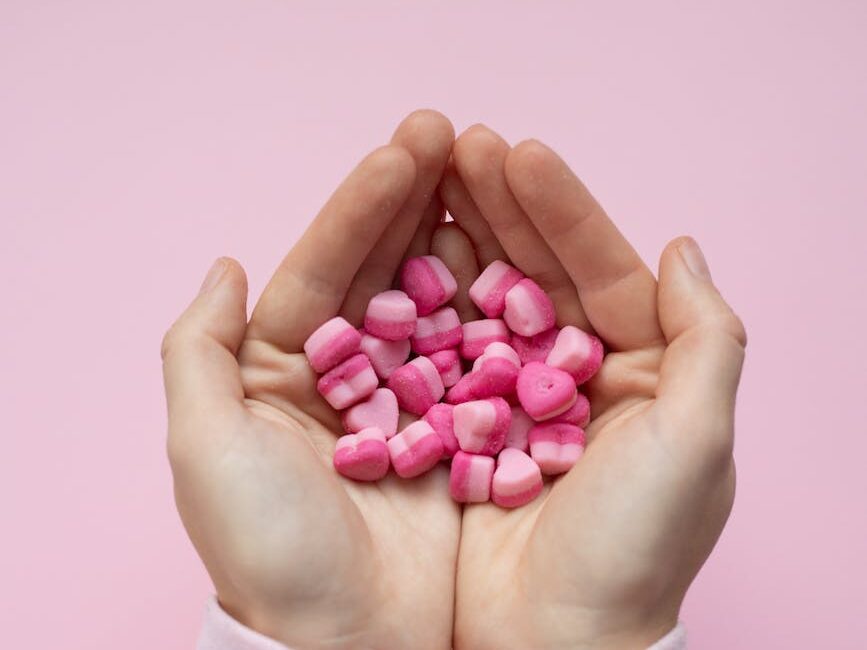 person showing small candies in shape of hearts in hands