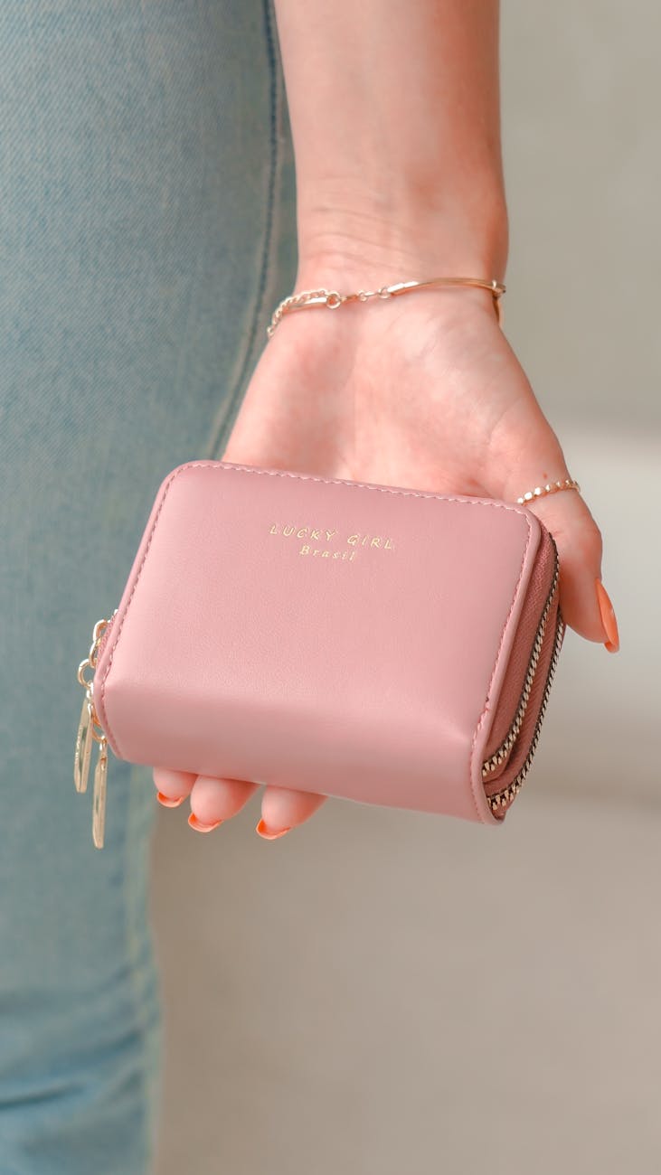 a person holding pink bifold wallet